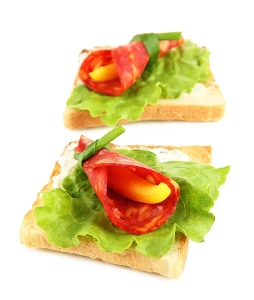 Rolos de salame com pedaços de páprica no interior, em pão torrado, isolados em branco — Fotografia de Stock