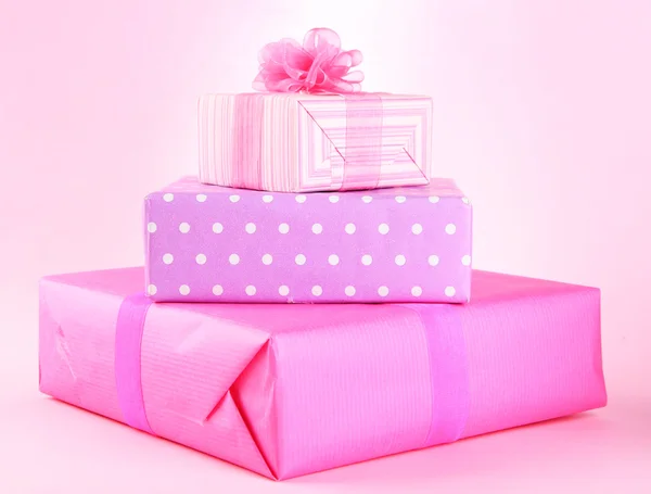 Regalos brillantes con lazos sobre fondo rosa — Foto de Stock