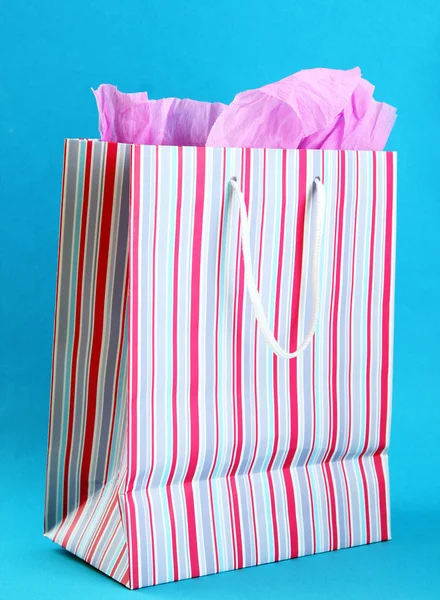 Mavi arka plan üzerinde çizgili alışveriş çantası — Stok fotoğraf