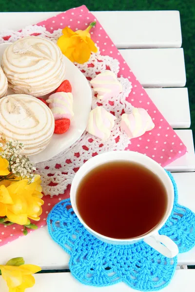 Beautiful composition with cup of tea and marshmallow on wooden picnic table close-up — Stock Photo, Image