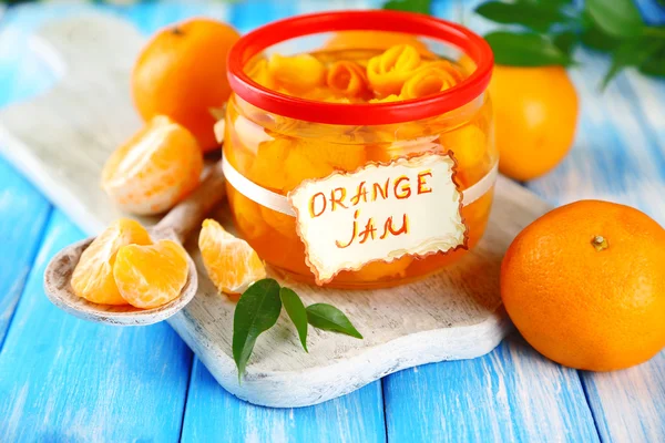 Oranžový jam s kůrou a mandarinky, na modré dřevěný stůl — Stock fotografie