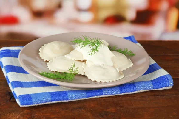 Tasty dumplings on plate, on wooden table — Zdjęcie stockowe