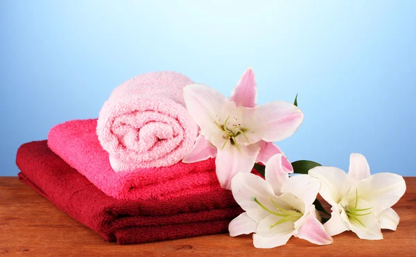 Stack of towels with pink lily on blue backgroun — Stock Photo, Image