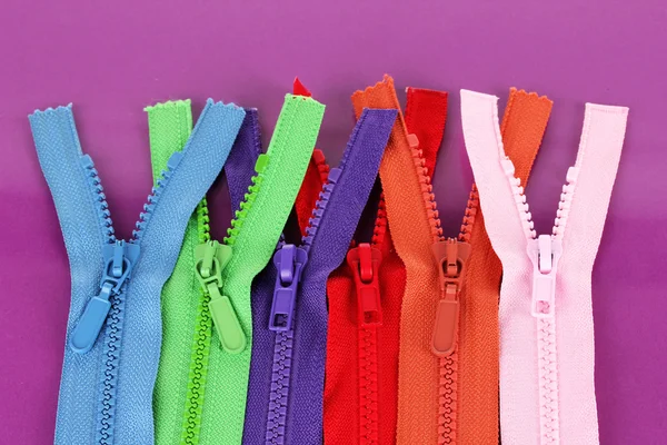 Multicolored zippers on purple background — Stock Photo, Image