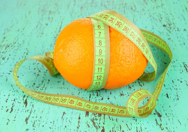 Naranja con cinta métrica, sobre fondo de madera de color —  Fotos de Stock