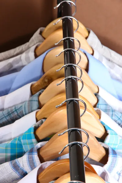 Camisas masculinas em cabides no fundo marrom — Fotografia de Stock