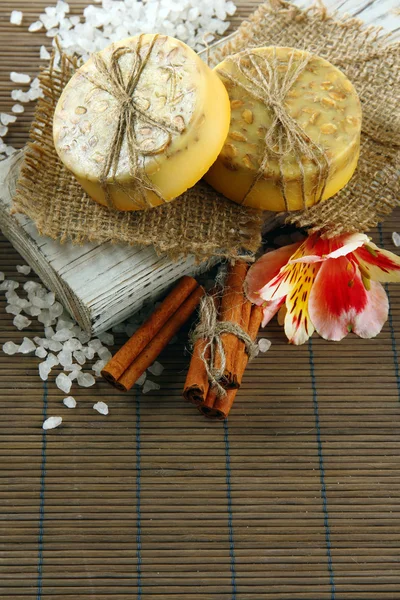 Hand-made soap and sea salt on grey bamboo mat — Stock Photo, Image