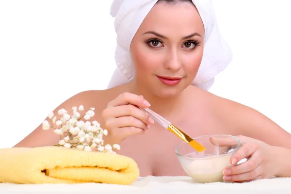 Beautiful young woman with cream for face mask and towel on her head isolated on white — Stock Photo, Image