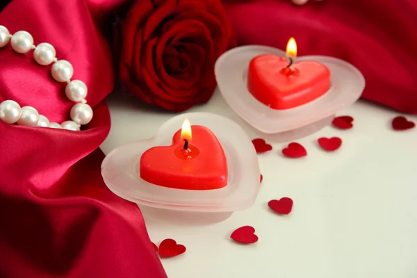 Hermosas velas y rosa sobre fondo de seda roja — Foto de Stock