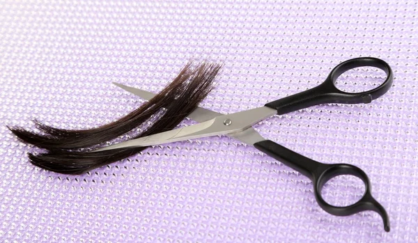 Pieces of hair cut with scissors on purple background — Stock Photo, Image