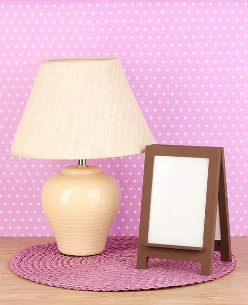 Brown photo frame and lamp on wooden table on lilac wall background — Stock Photo, Image