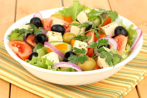 Frischer Salat im Teller auf Holztisch — Stockfoto