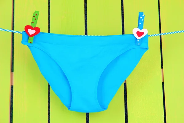 Womans panties hanging on a clothesline, on green wooden background — Stock Photo, Image