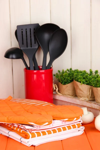 Kitchen settings: utensil, potholders, towels and else on wooden table — Stock Photo, Image