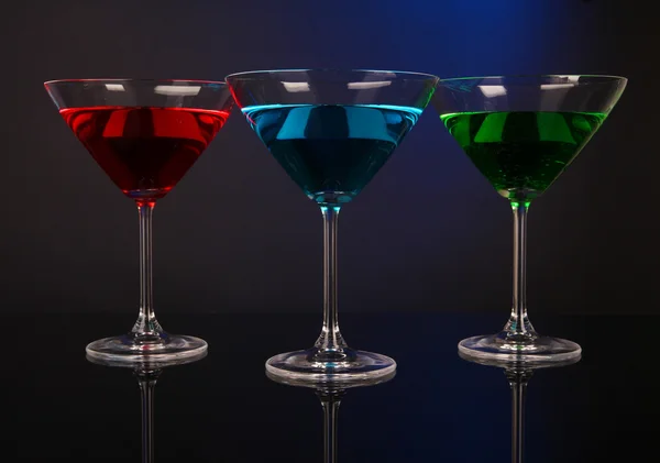 Coquetéis alcoólicos em copos de martini no fundo azul escuro — Fotografia de Stock