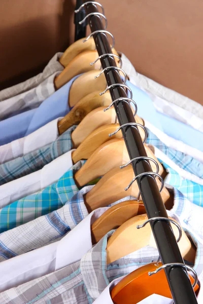 Men's shirts on hangers on brown background — Stock Photo, Image