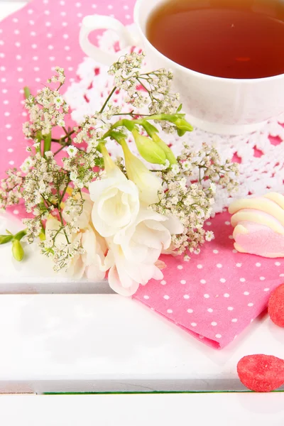 Beautiful composition with cup of tea and flowers on wooden picnic table close-up — Stock Photo, Image