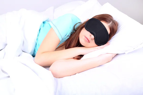 Vacker ung kvinna som sover i sängen med eye mask — Stockfoto