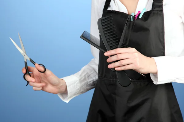 Peluquería en uniforme con herramientas de trabajo, sobre fondo de color — Foto de Stock