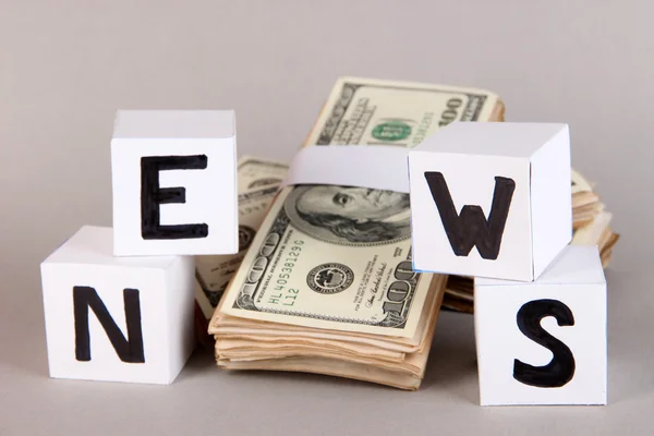 Vitboken kuber som heter "Nyheter" med pengar på grå bakgrund — Stockfoto