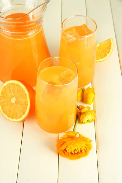 Glasögon och tillbringare med apelsinjuice på vit trä bakgrund — Stockfoto