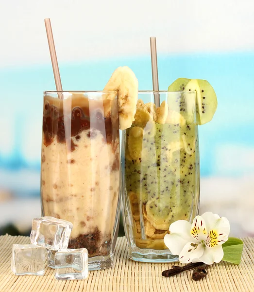 Lahodné ovocné koktejly na tabulce na modrém pozadí — Stock fotografie