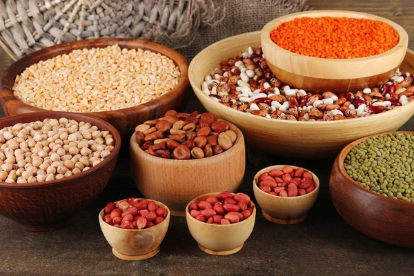 Different kinds of beans in bowls on wooden background — Stock Photo, Image