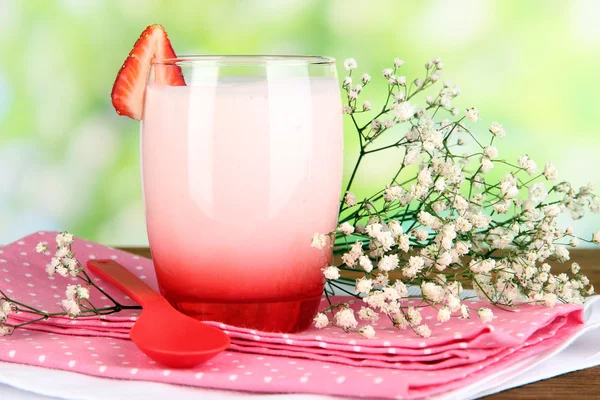 Heerlijke aardbeien yoghurt in glas op houten tafel op natuurlijke achtergrond — Stockfoto