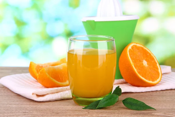 Glas juice, Citruspress och mogen orange på brun träbord — Stockfoto