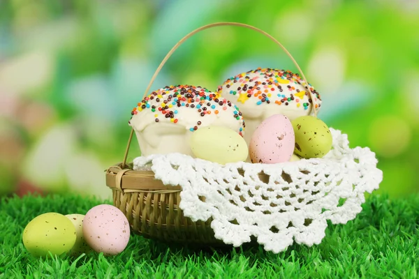 Pastel de Pascua con huevos en canasta de mimbre sobre hierba — Foto de Stock