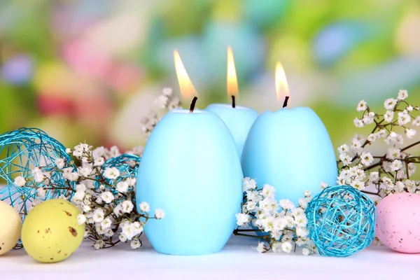 Easter candles with flowers on bright background — Stock Photo, Image
