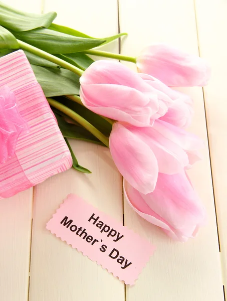 Beautiful bouquet of pink tulips and gift for Mother's Day on white wooden background — Stock Photo, Image