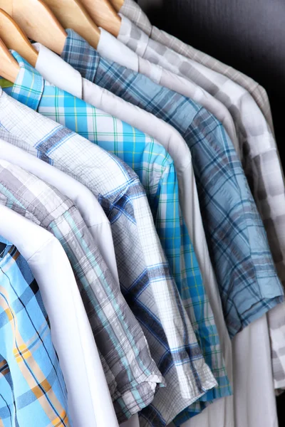 Men's shirts on hangers on wooden background — Stock Photo, Image