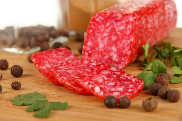 Sabroso salami sobre tabla de madera aislado en blanco — Foto de Stock