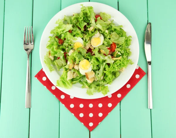 Renkli ahşap zemin üzerinde beyaz tabakta Sezar salatası — Stok fotoğraf