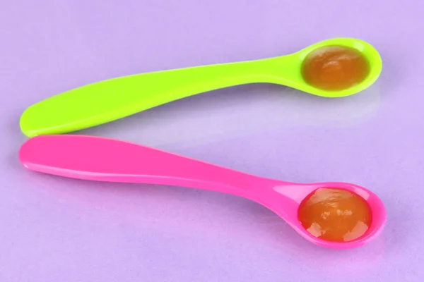Color spoons for baby food on purple background — Stock Photo, Image