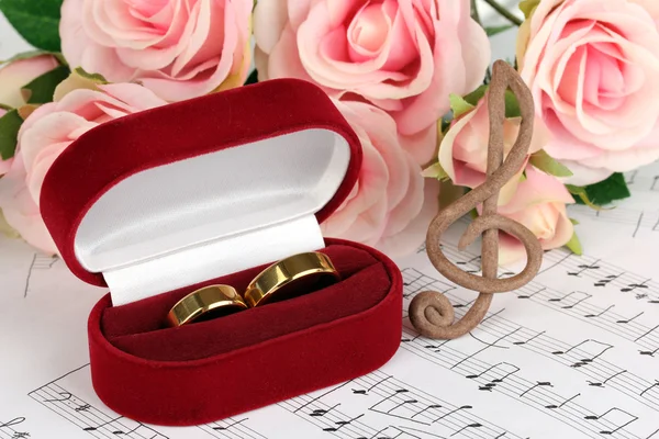 Clave triple, rosas y cajas con anillos de boda sobre fondo musical —  Fotos de Stock