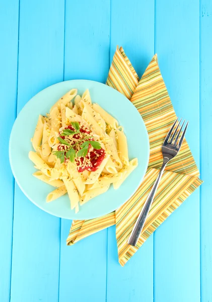 Danie makaron Rigatoni z sosem pomidorowym na niebieskim drewnianym stołem — Zdjęcie stockowe