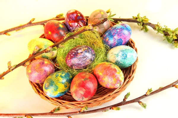 Hermosos huevos de Pascua en canasta de mimbre sobre fondo claro — Foto de Stock