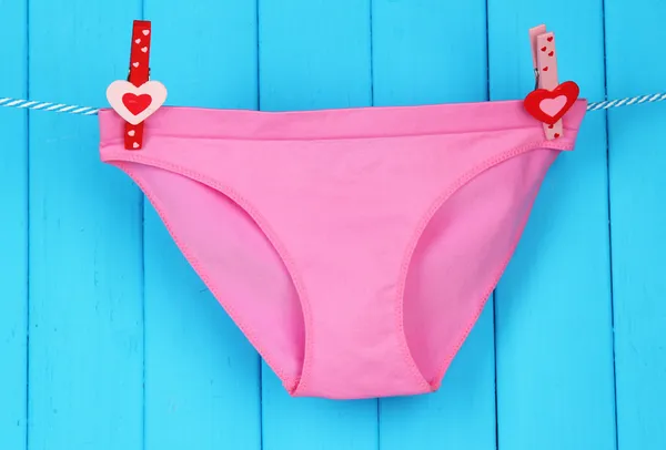 Womans panties hanging on a clothesline, on blue wooden background — Stock Photo, Image