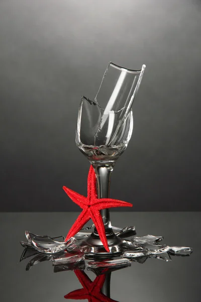 Broken wineglass with sea star on grey background — Stock Photo, Image