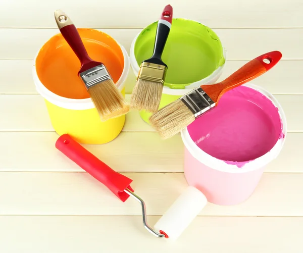 Set for painting: paint pots, brushes, paint-roller on white wooden table — Stock Photo, Image