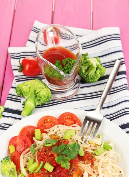 Tasty spaghetti with sauce and vegetables on plate on wooden table close-up — Stock Photo, Image