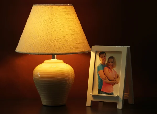 白色相框和褐色的墙壁背景上的木桌上的灯 — 图库照片