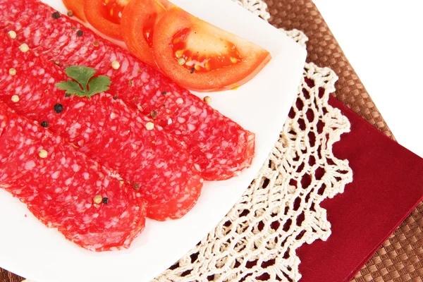 Salame saporito su piatto su tovagliolo isolato su bianco — Foto Stock