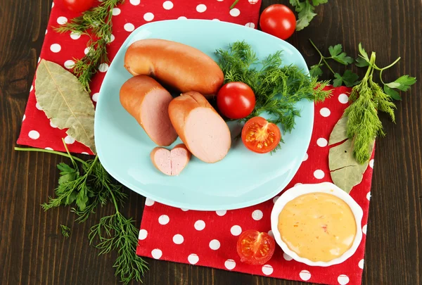 Salsicha, verduras, tomate na placa na mesa de madeira — Fotografia de Stock