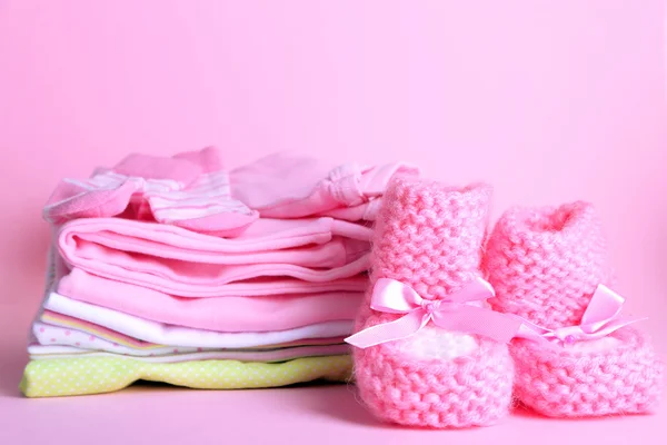 Hög med babykläder på rosa bakgrund — Stockfoto