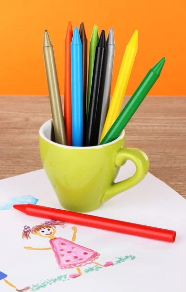 Buntstifte in Tasse auf Tisch auf orangefarbenem Hintergrund — Stockfoto