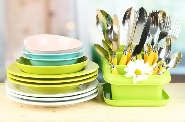 Placas, garfos, facas, colheres e outros utensílios de cozinha sobre fundo brilhante — Fotografia de Stock