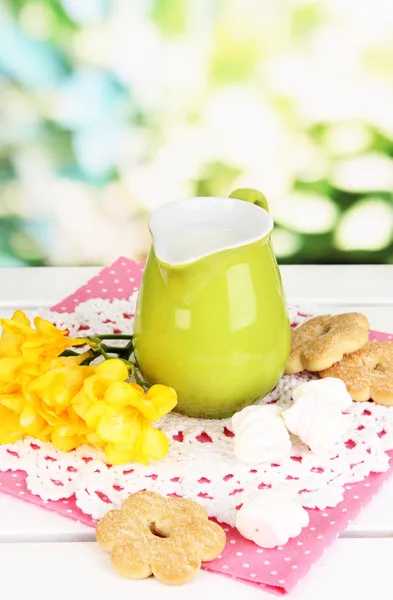 Beautiful composition of milk and cookies on wooden picnic table on natural background — Stock Photo, Image